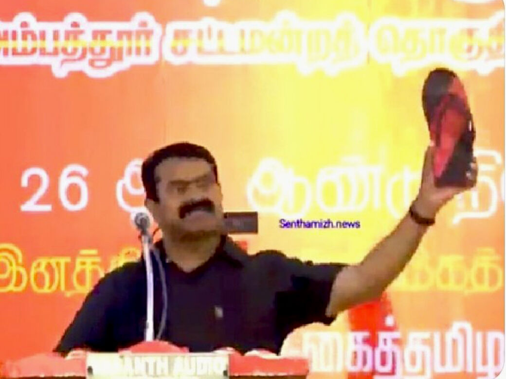 கருப்பு, சிவப்பு நிறத்திலான செருப்பை கழட்டி காண்பித்து தி.மு.க.வை விமர்சித்த சீமான்!